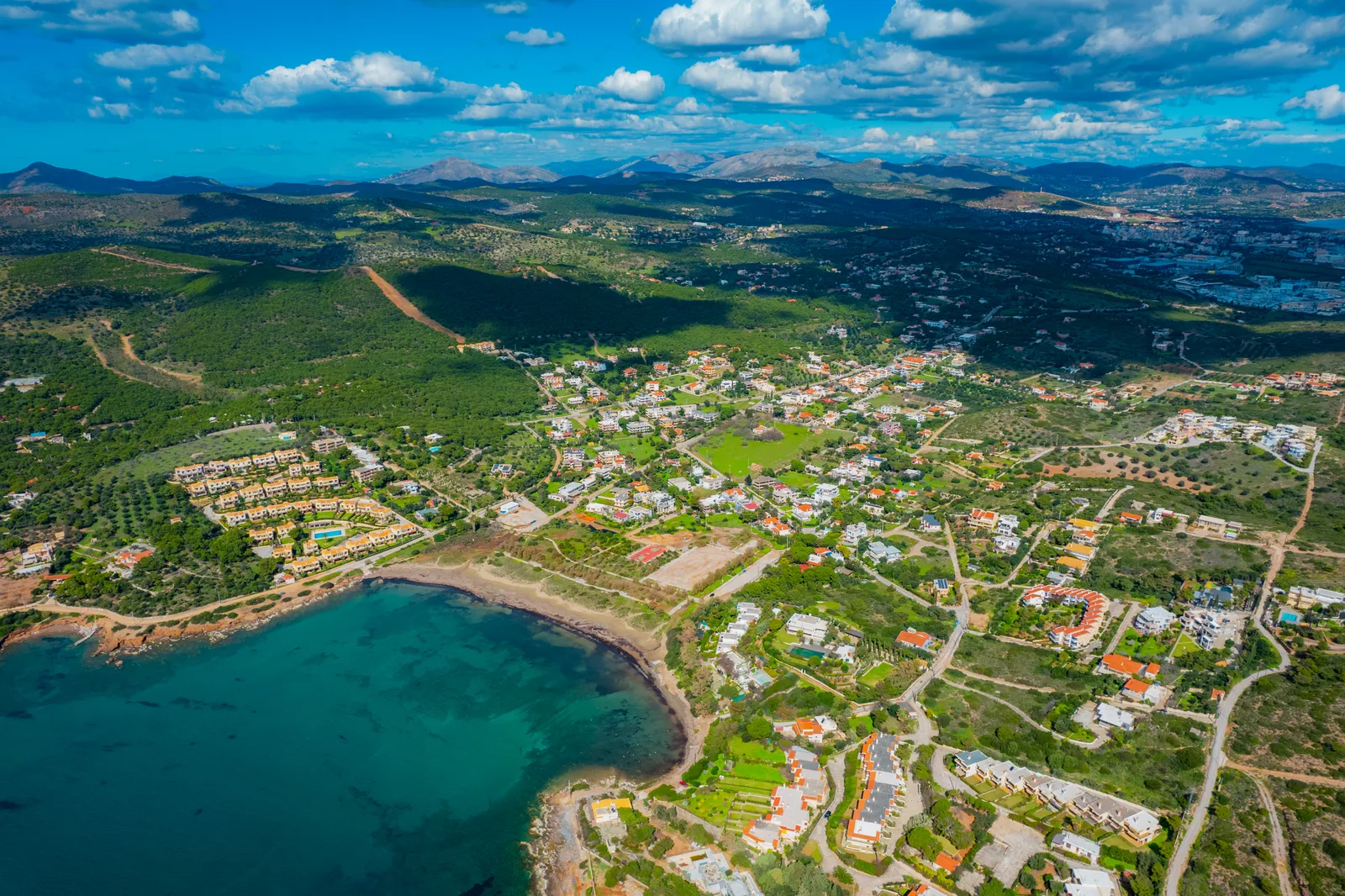 Aerial view of a coastal bay with clear turquoise water and a hillside town