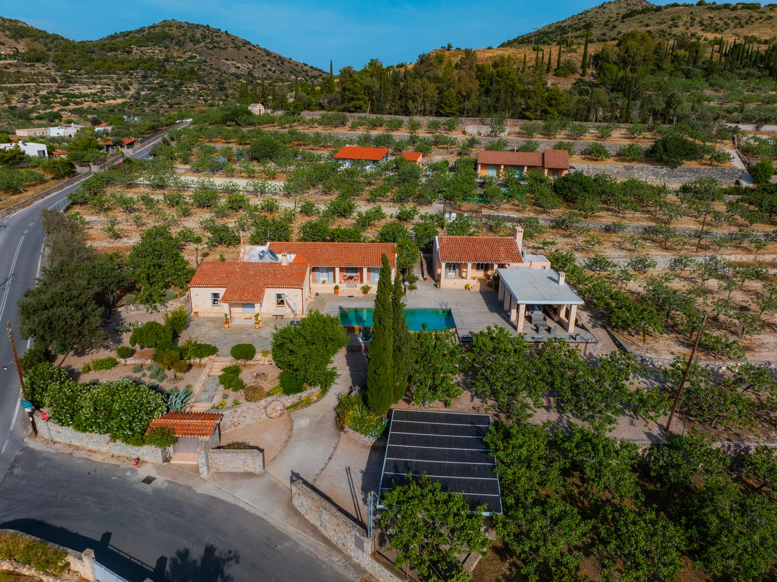 Aerial view of a villa with a pool among olive groves and hills