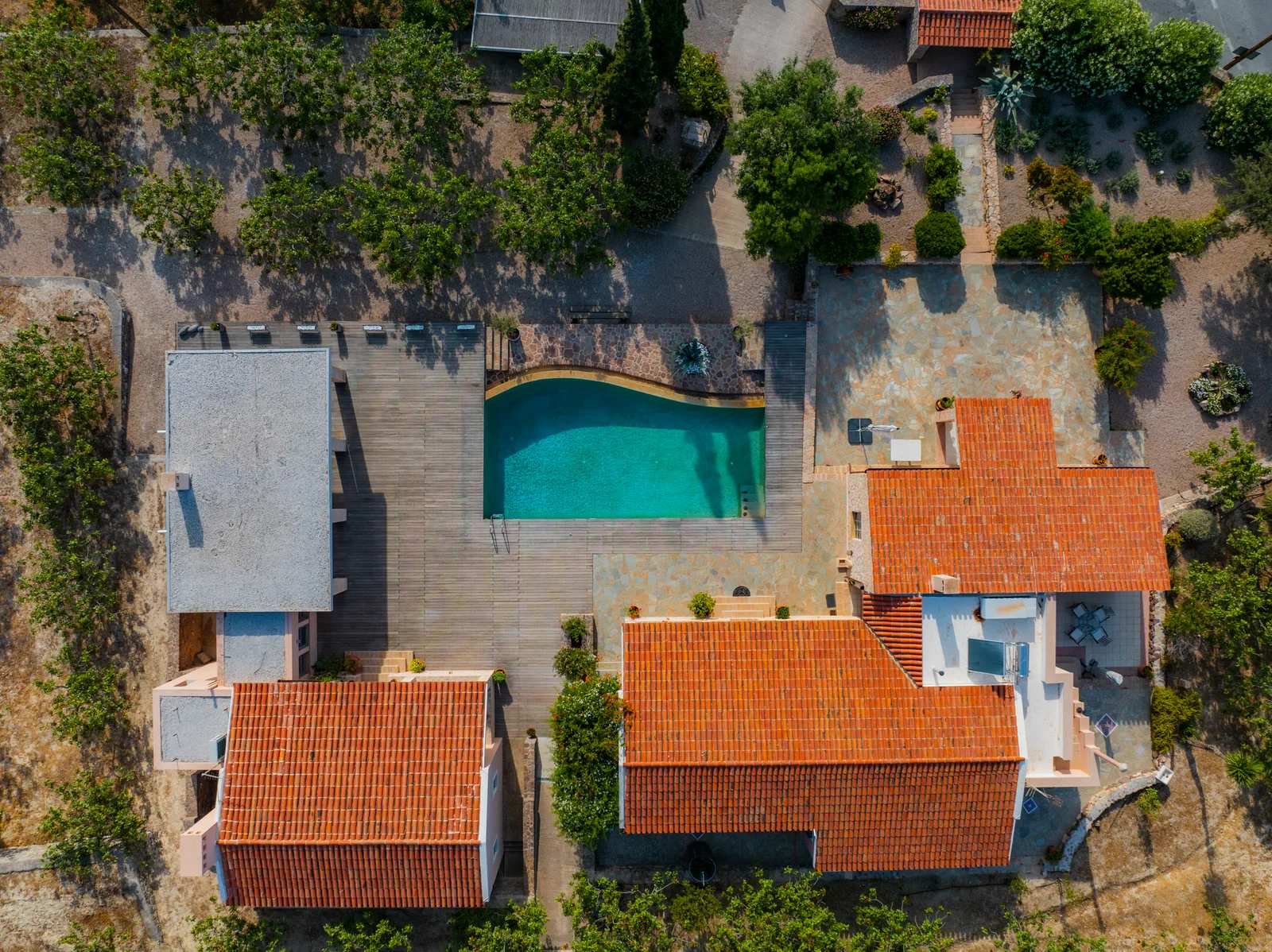 Overhead view of a villa with a curved pool and terracotta roofs