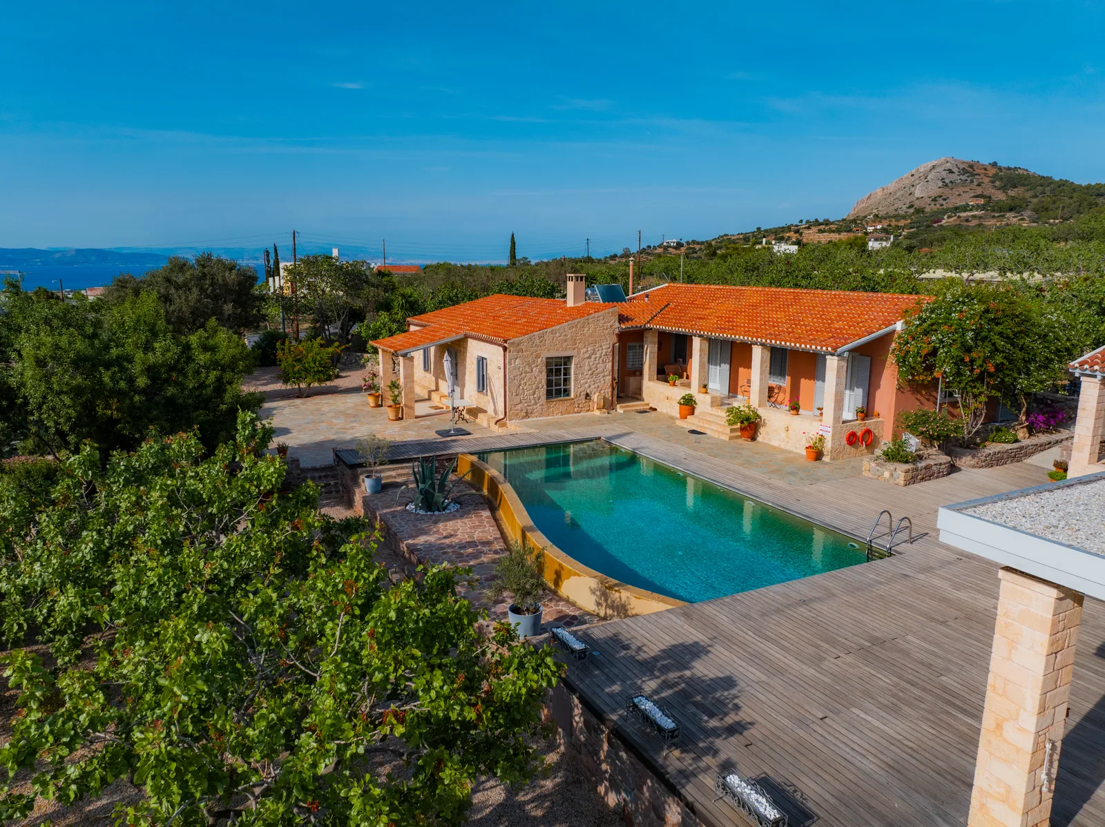 Aerial view of a stone villa with a pool and a terrace close to the sea