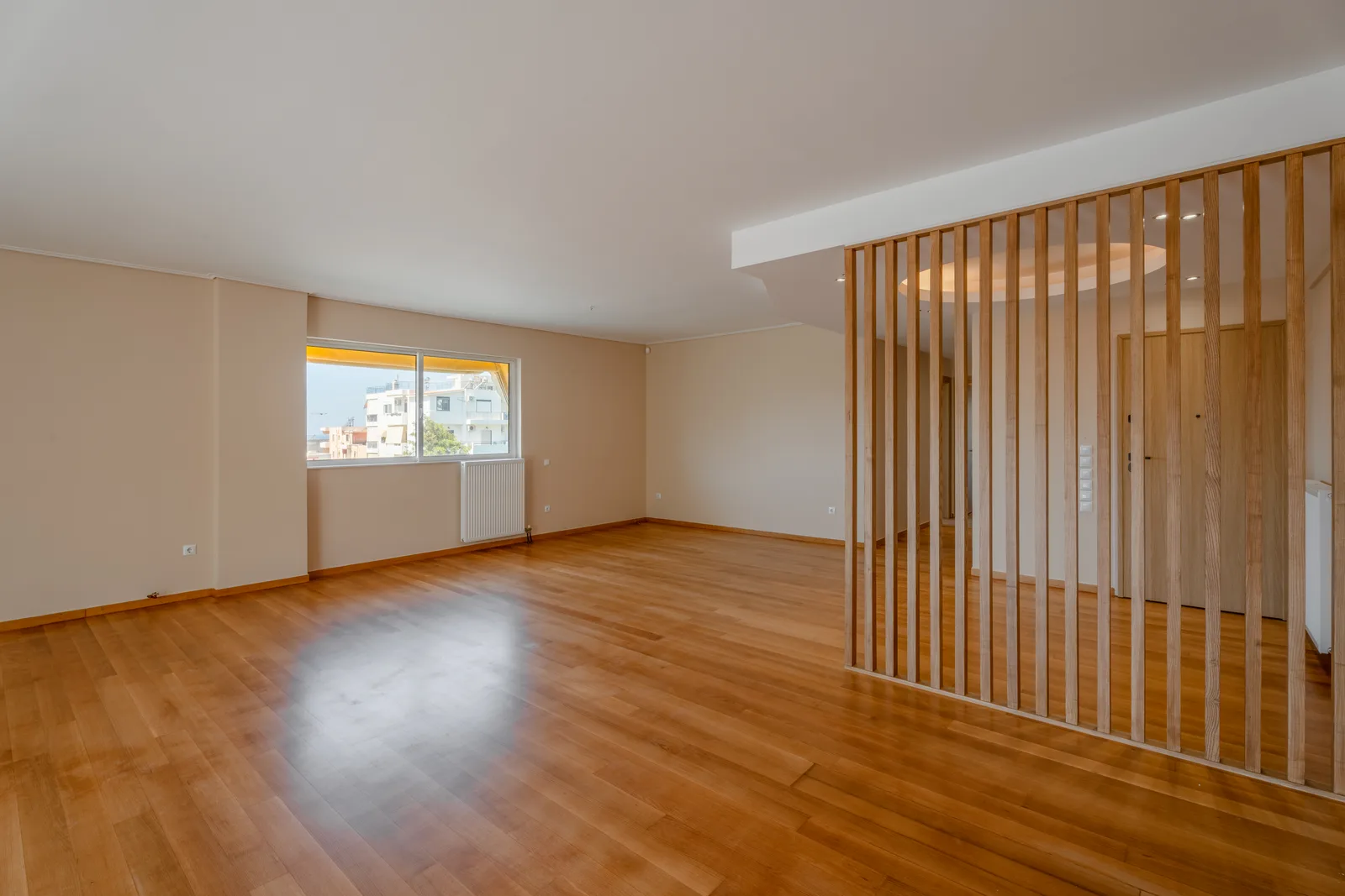 Empty living room with a wooden floor and a slatted room divider