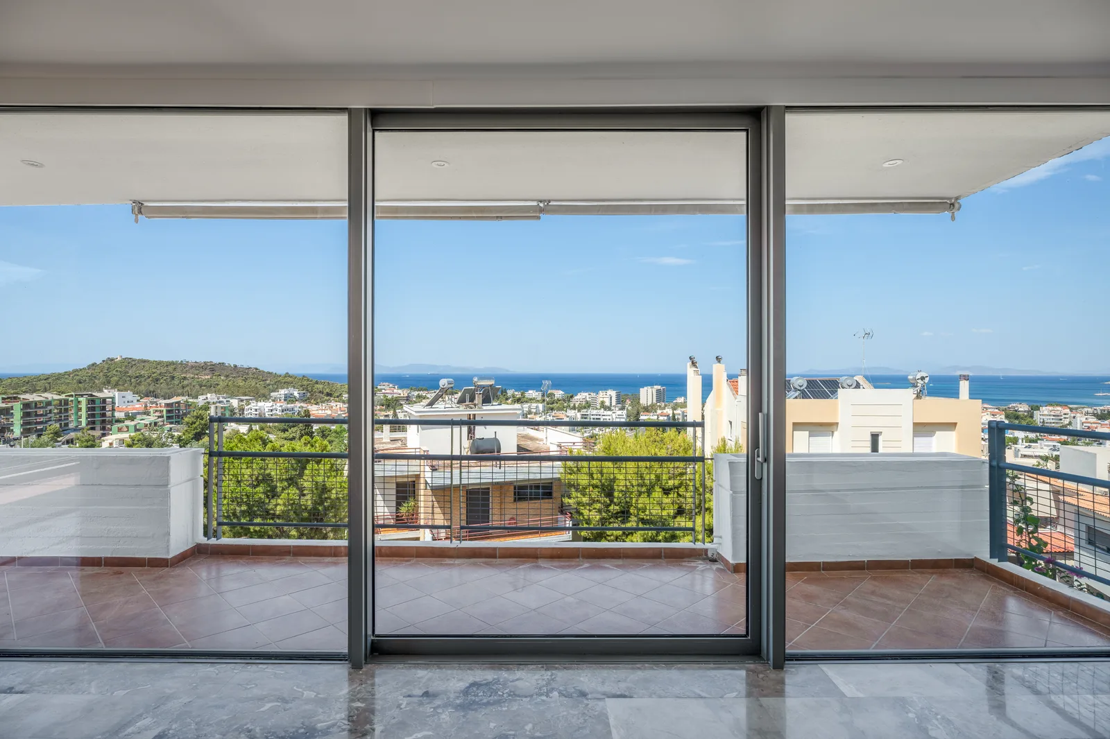 Balcony with floor to ceiling glass doors overlooking rooftops and hills