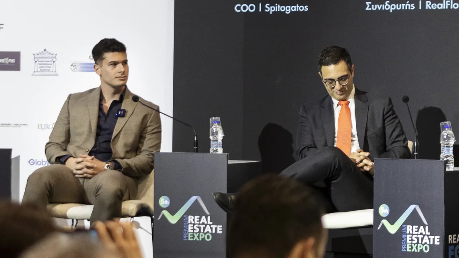 Two speakers seated on stage during a panel at the Premium Real Estate Expo in Athens